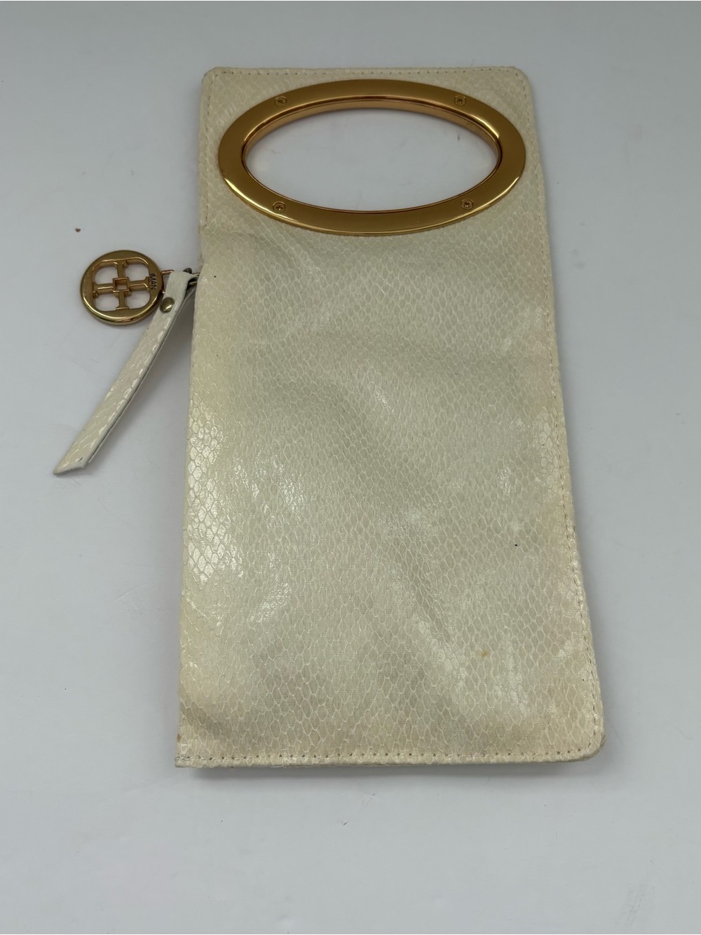Ivory faux-snakeskin IMAN clutch featuring a striking gold tone oval top handle